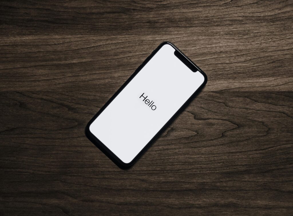pexels photo 699122 699122 A smartphone displaying 'Hello' on a wooden surface, showcasing modern technology.